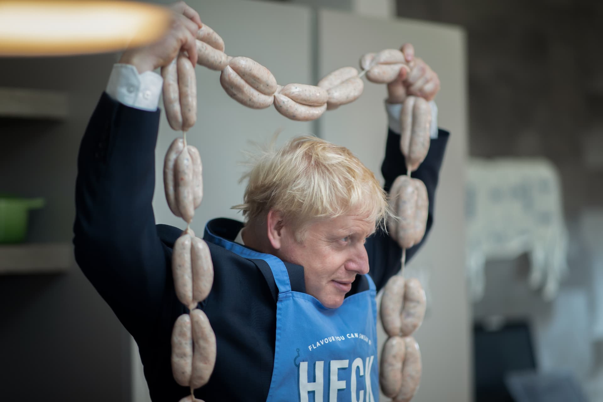 Boris Johnson holding up a chain of HECK sausages