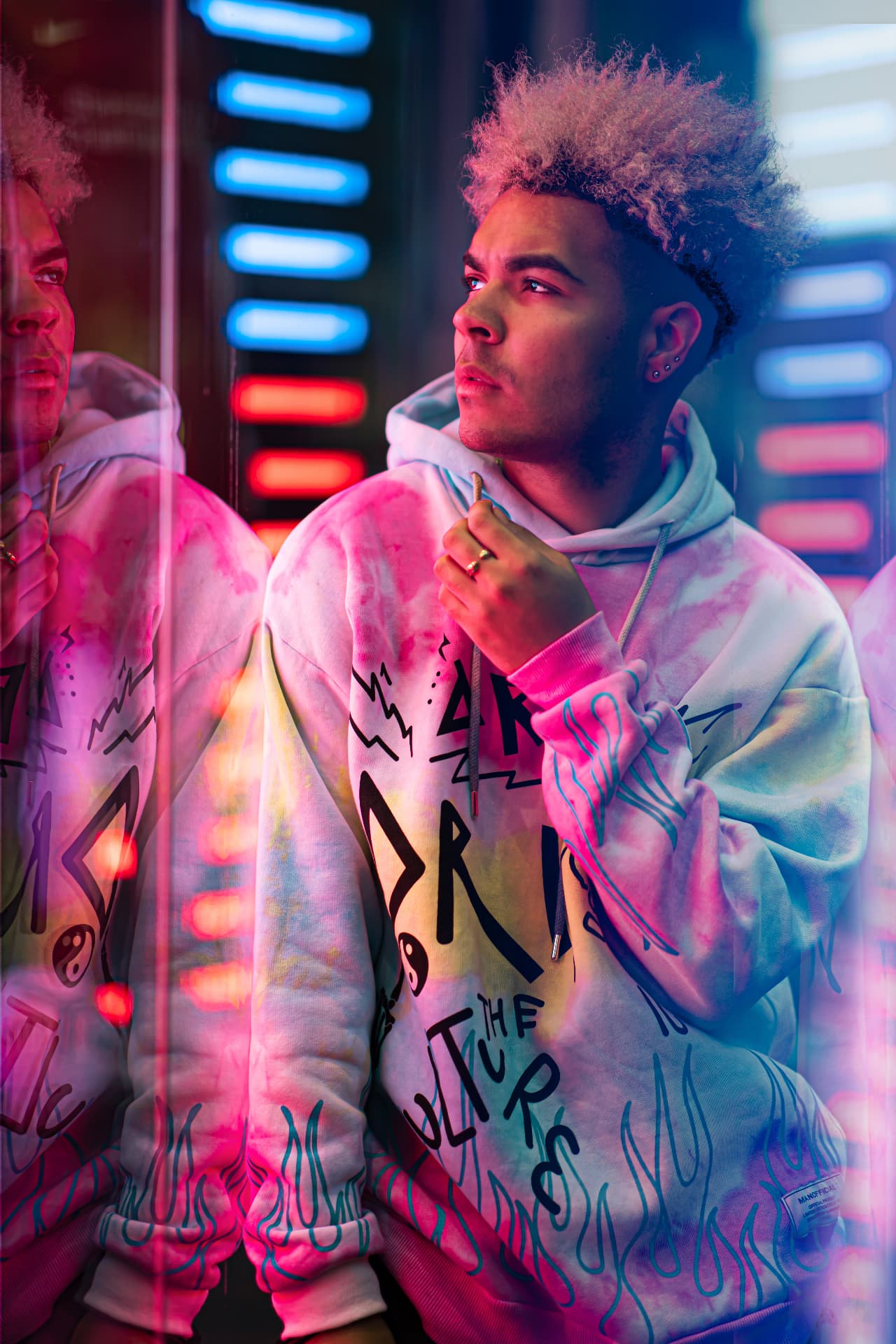 Streetwear model in a tie-dye hoodie lit by neon tubes