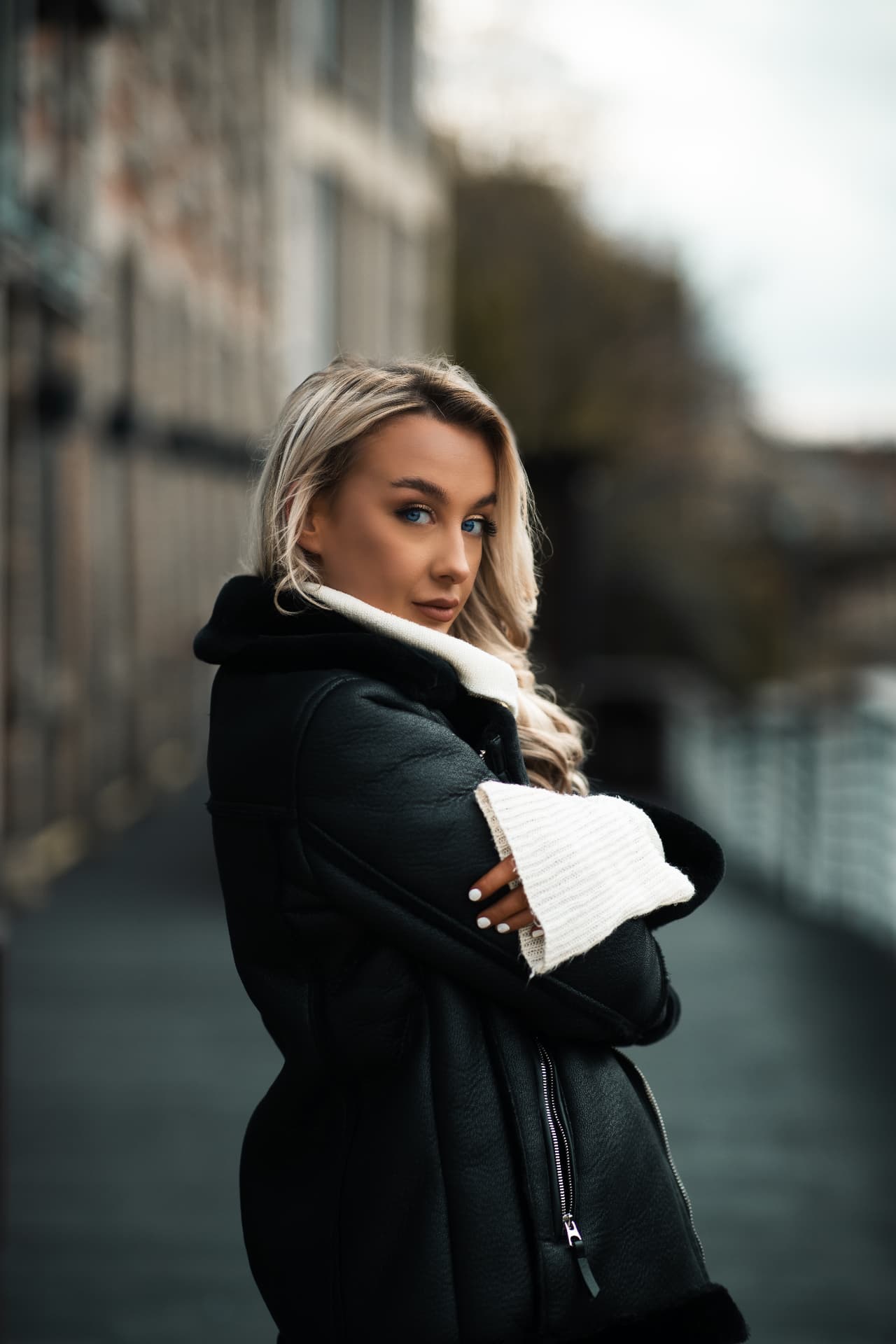 Fashion model in a shearling leather coat on a riverside street