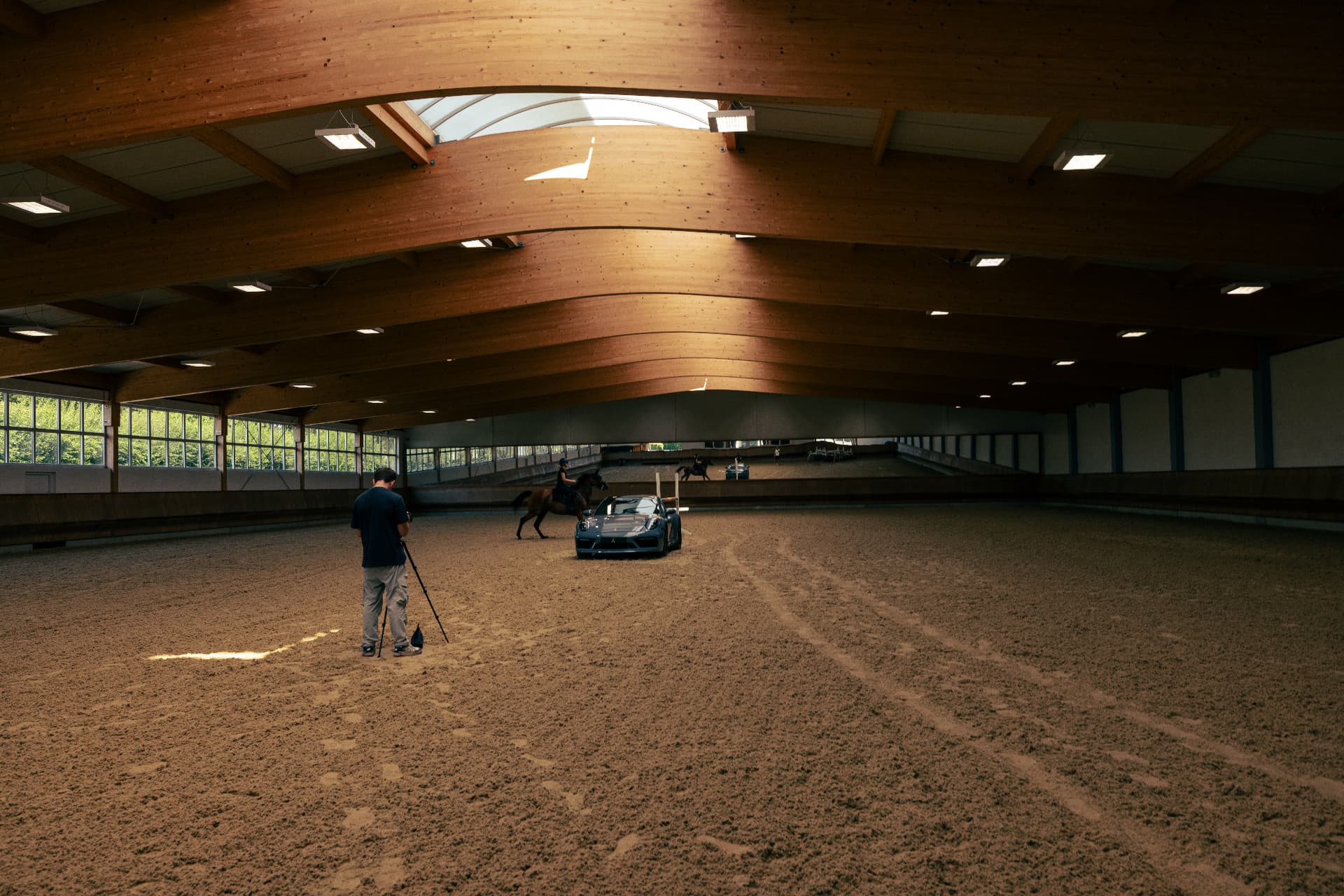 Behind the scenes in an equestrian arena with a Porsche and horse for a luxury automotive campaign