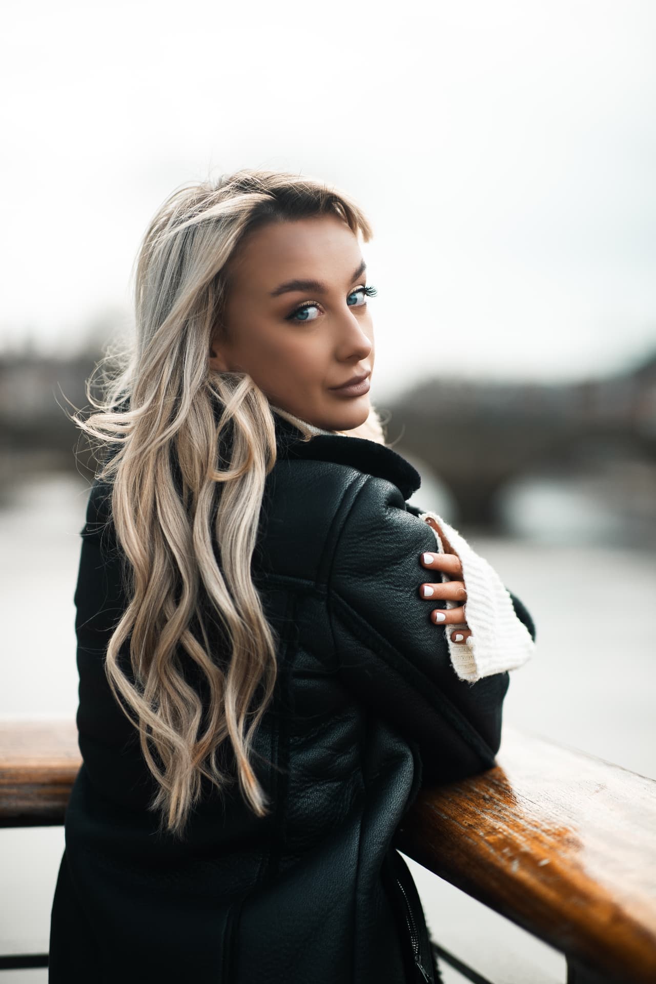 Fashion model in a leather jacket on a riverside bridge