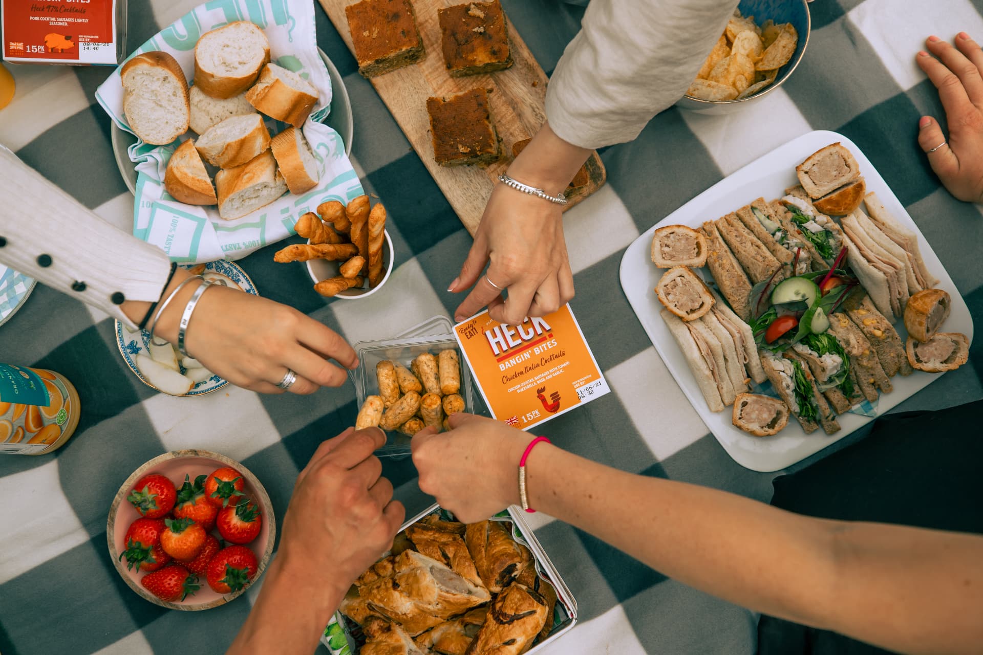 Overhead shot of a HECK BBQ picnic spread with sausage rolls and sandwiches